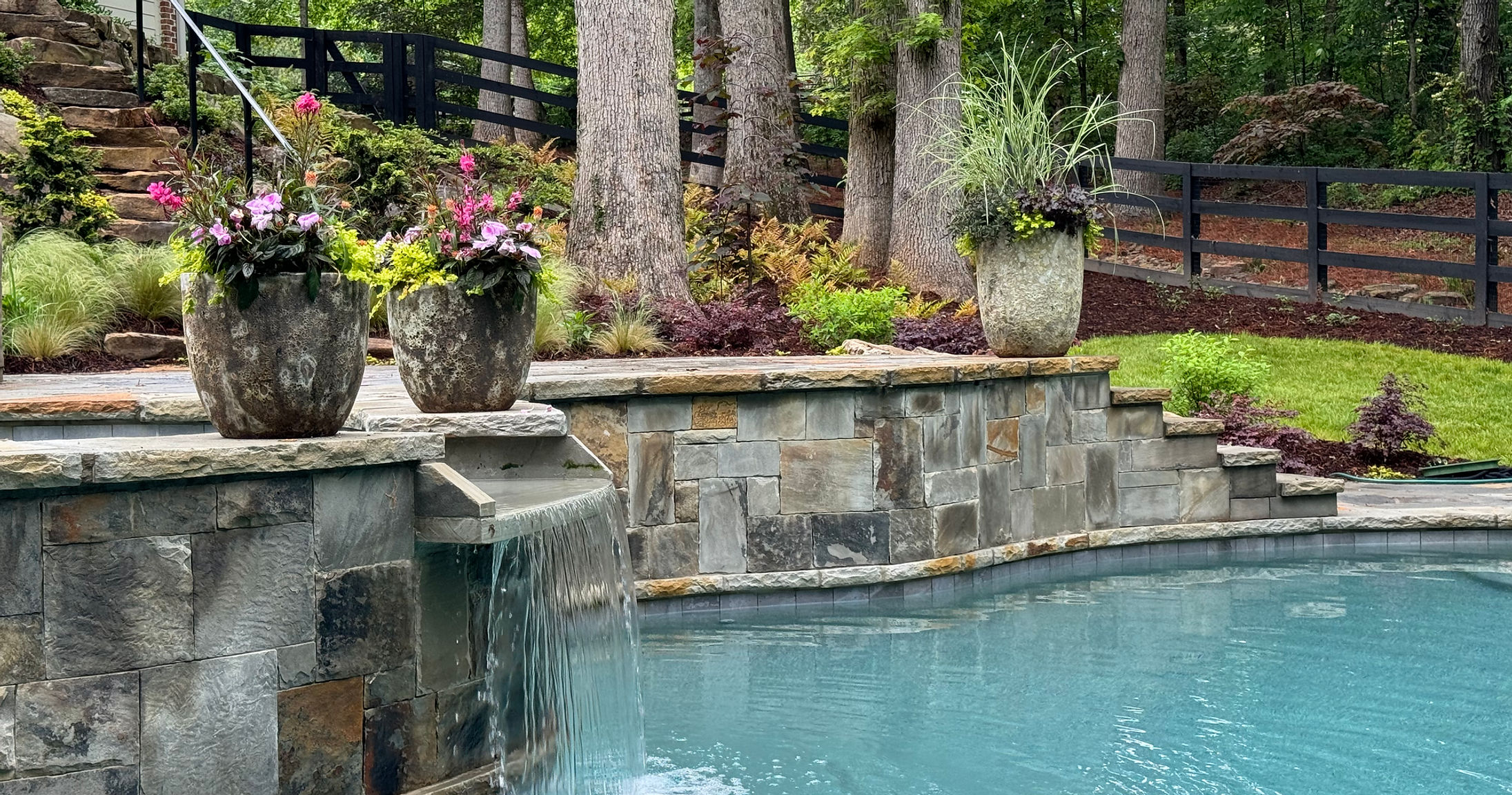 Stone water feature and pool surrounded by landscaping — Greg Horton Outdoors project