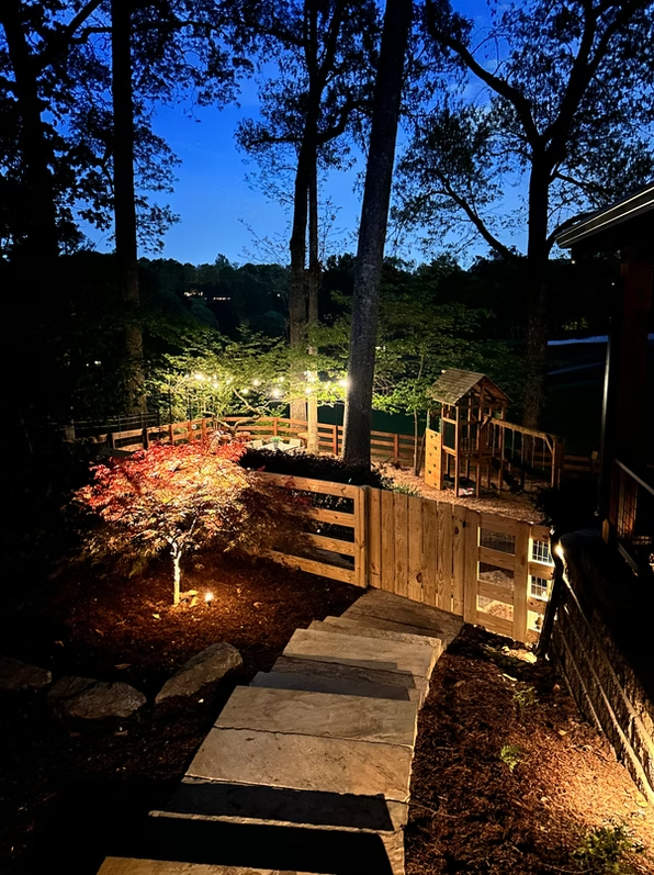 Multi-level deck with stone path and landscape lighting at night